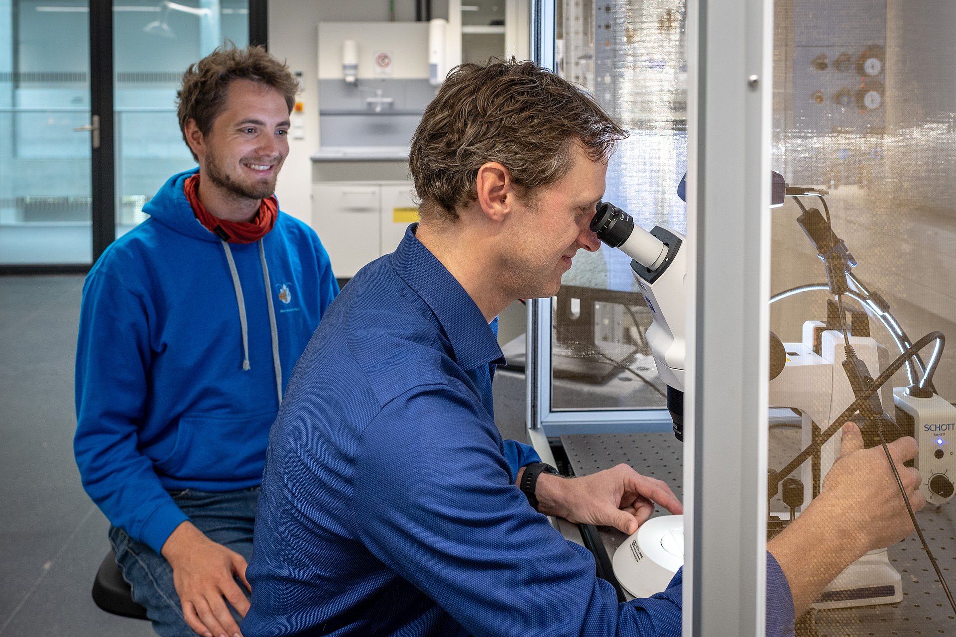 Prof. Bernhard Wolfrum (front) and Lukas Hiendlmeier check the electrodes under the microscope for their electrical and mechanical functionality.