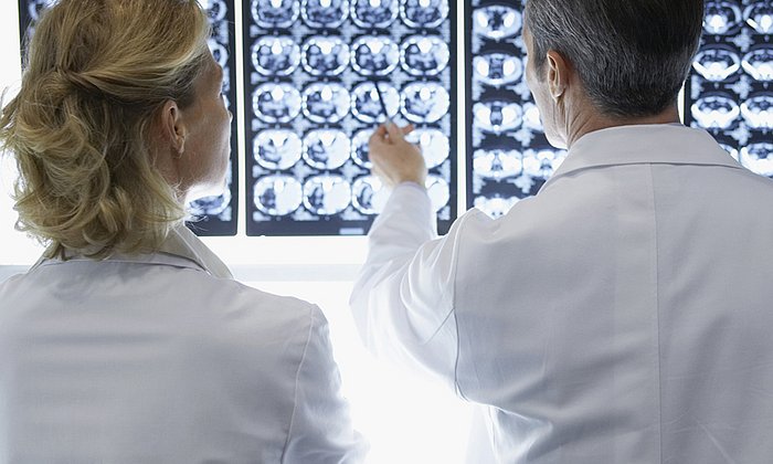 Rear view of a male and female doctor discussing brain scans in hospital.