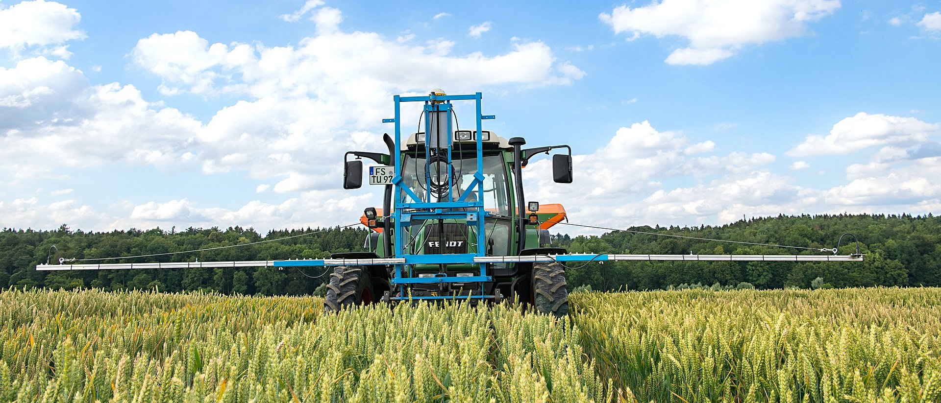 Traktor im Getreidefeld mit vorne angebrachter Vorrichtung mit Sensoren.