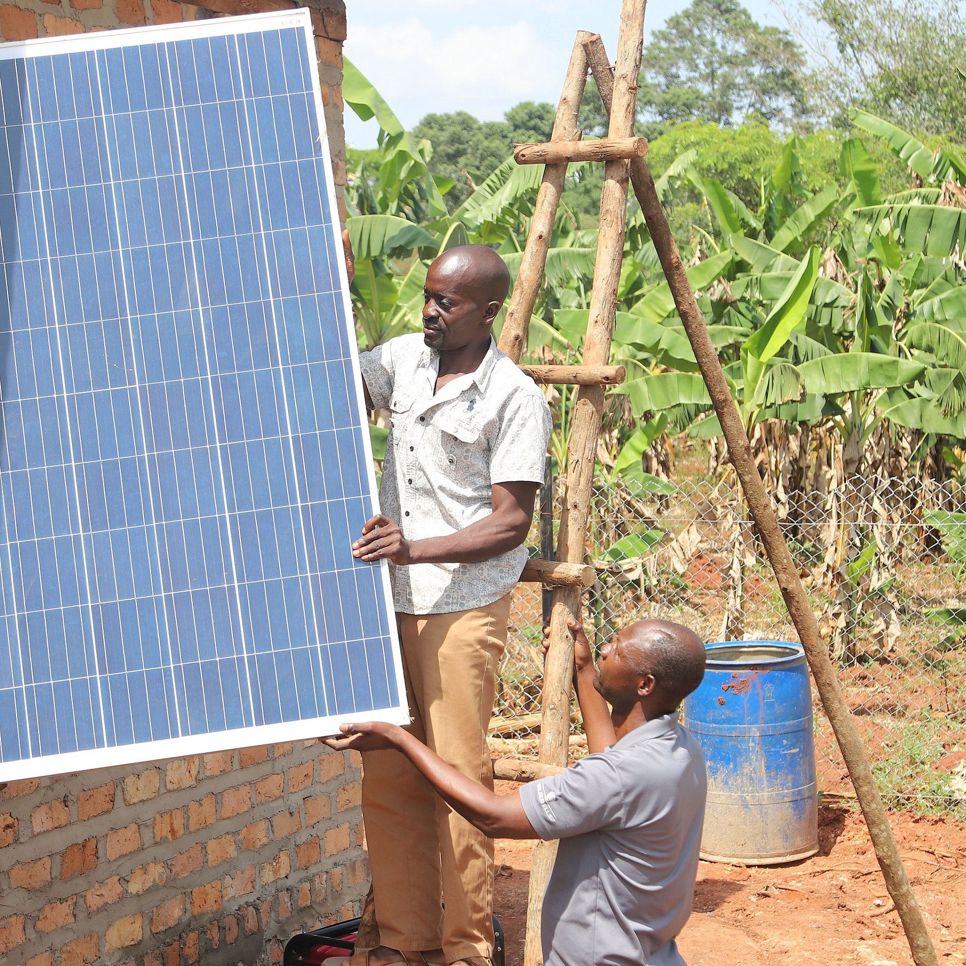 Two men install solar system in village environment.