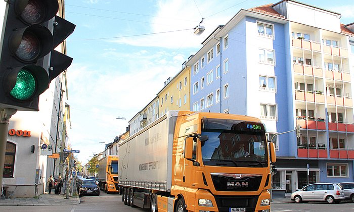 Ein Lkw der Firma MAN fährt durch die Stadt. Im Vordergrund zeigt eine Ampel grün.