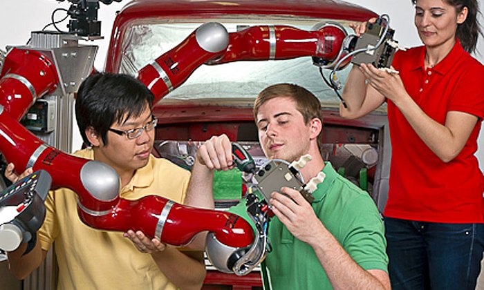 Young researchers working at a robot.