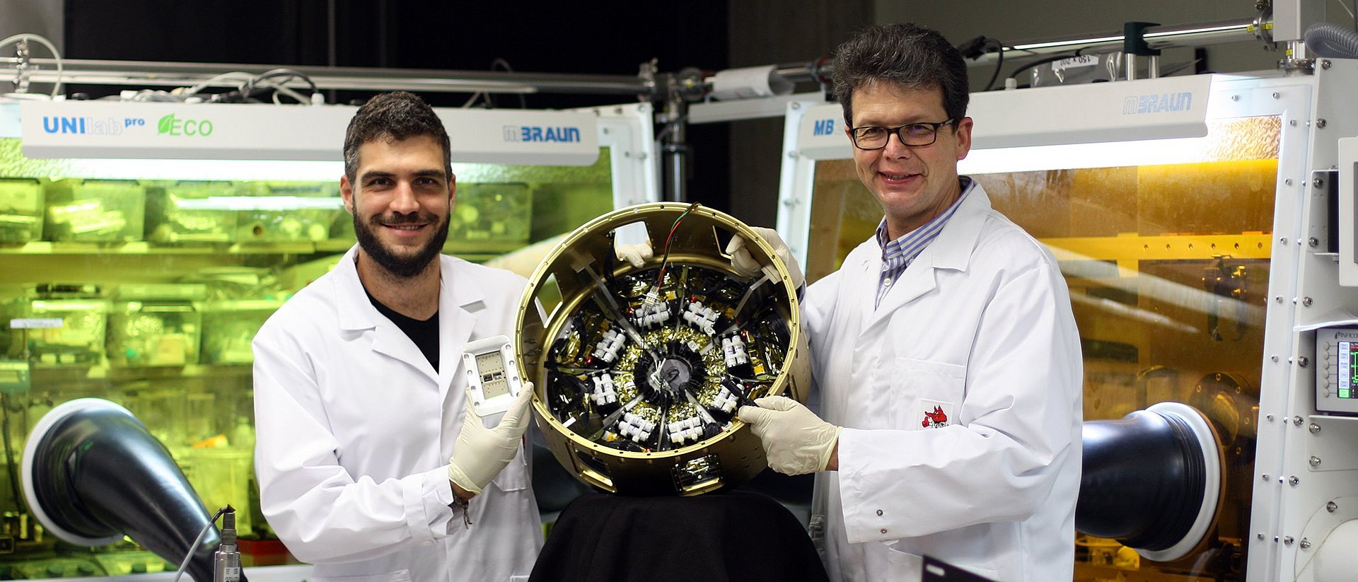 Prof. Dr. Peter Müller-Buschbaum (left) and Lennart Reb (right) in the laboratories of the Professorship of Functional Materials at the Technical University of Munich with the payload module “Organic and Hybrid Solar Cells In Space” (OHSCIS) in their hands.