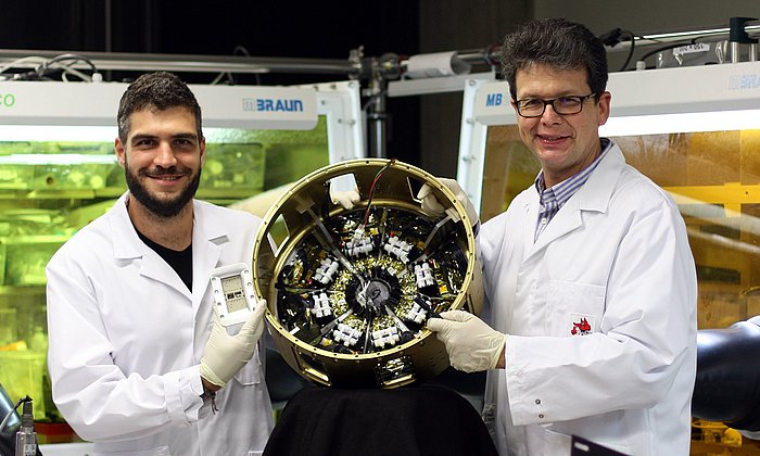 Prof. Dr. Peter Müller-Buschbaum (left) and Lennart Reb (right) in the laboratories of the Professorship of Functional Materials at the Technical University of Munich with the payload module “Organic and Hybrid Solar Cells In Space” (OHSCIS) in their hands.