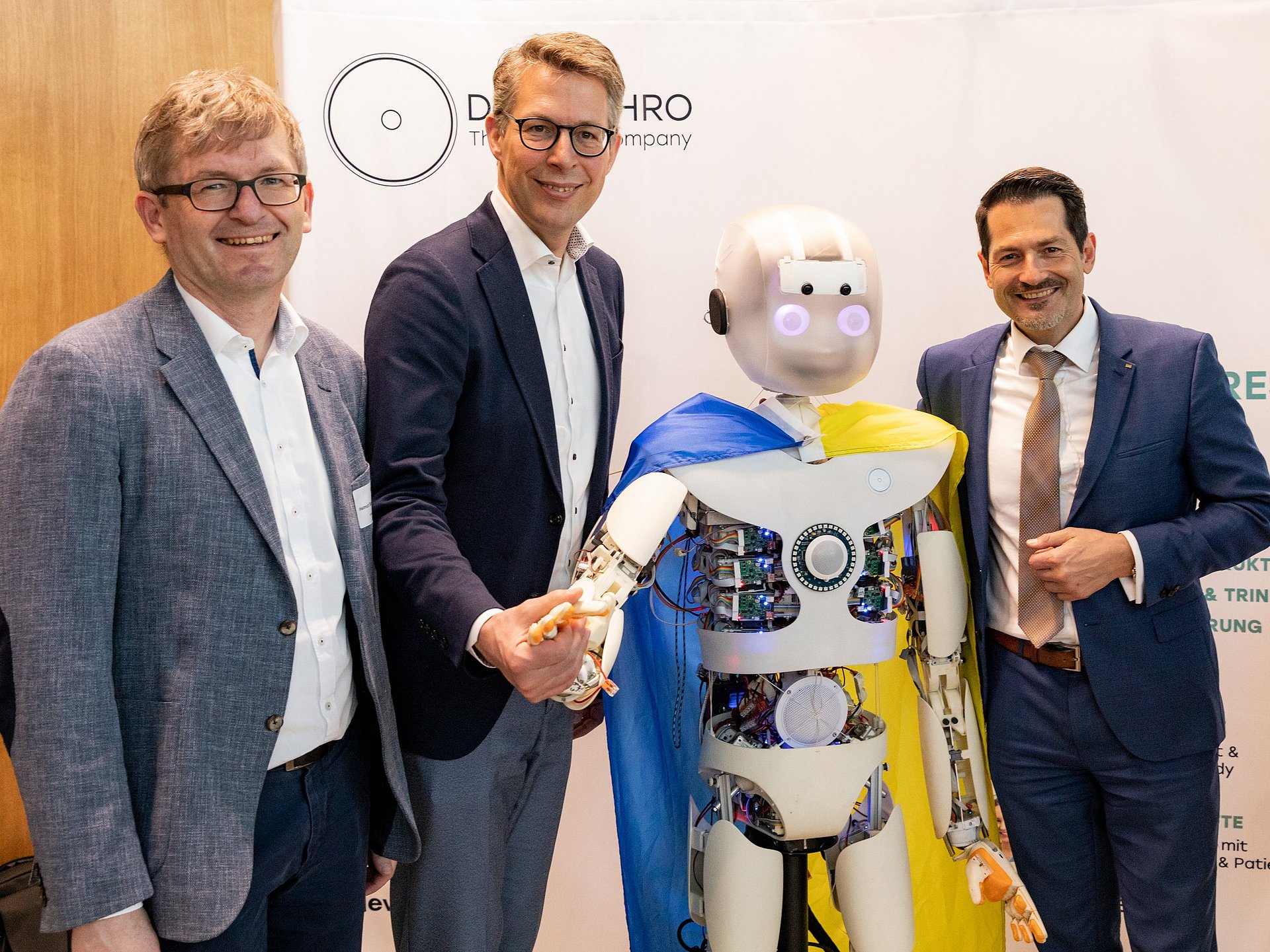 UnternehmerTUM CEO Prof. Helmut Schönenberger, Science Minister Markus Blume and TUM President Prof. Thomas F. Hofmann (from left) with a robot developed by the start-up Devanthro.