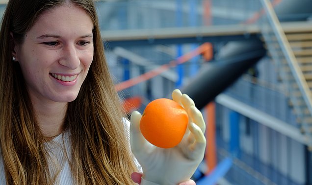 Doktorandin Johanna Happold zeigt, wie eine Handprothese mithilfe von Muskelsignalen greift.