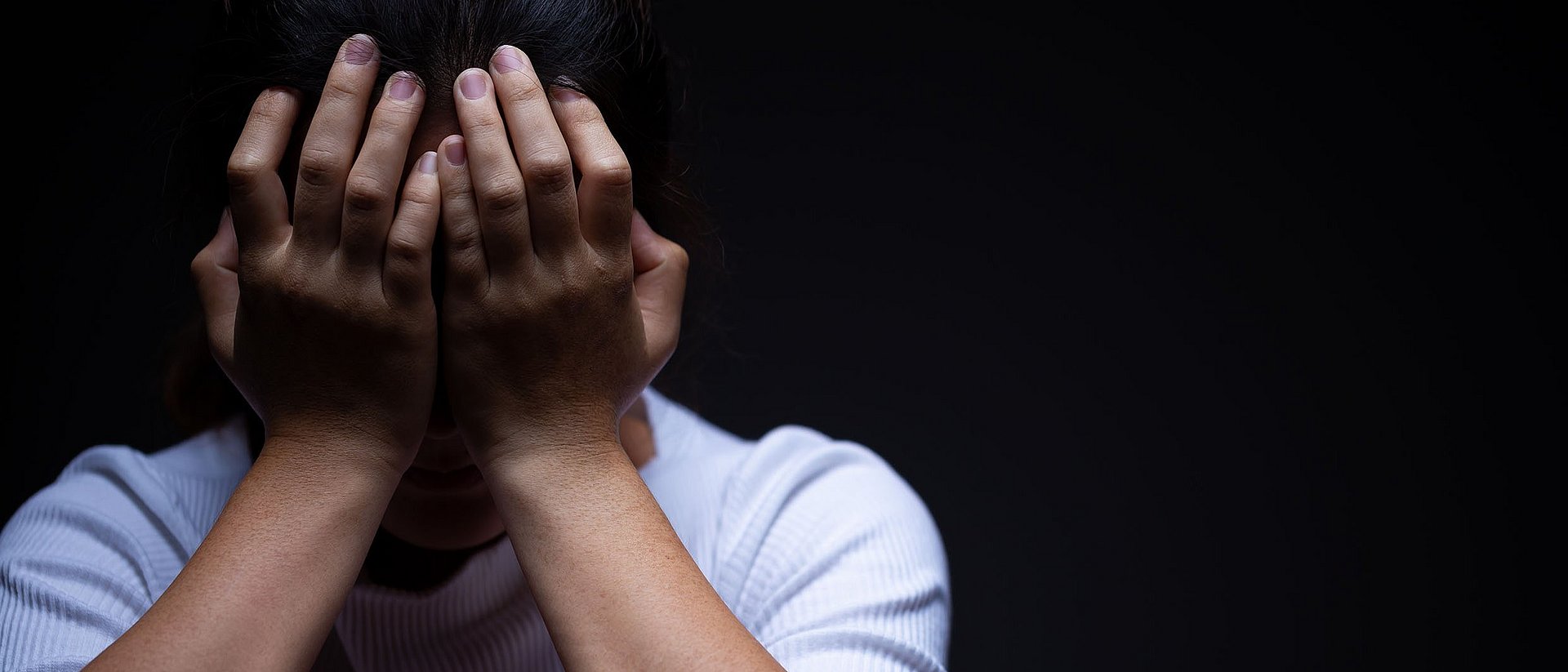 A woman puts her hands in front of her face