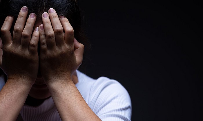 A woman  puts her hands in front of her face