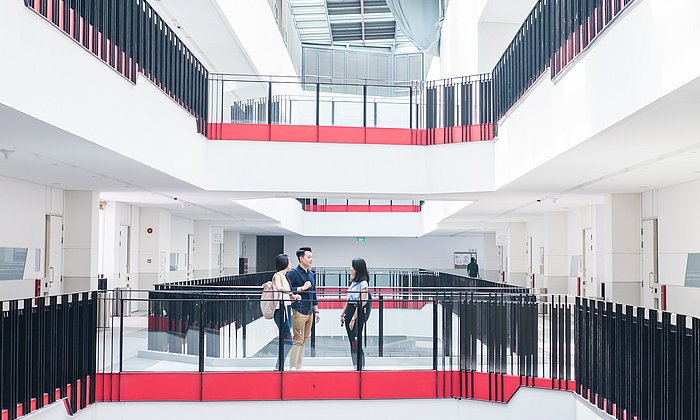 Zwei Studierende unterhalten sich in einem Treppenhaus. 