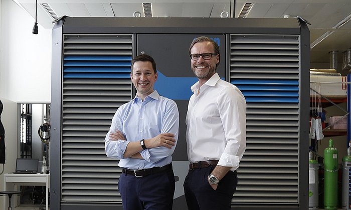 Andreas Sichert and Wolfgang Brand, executive directors of Orcan Energy, in front of their product, which produces electricity from waste heat.