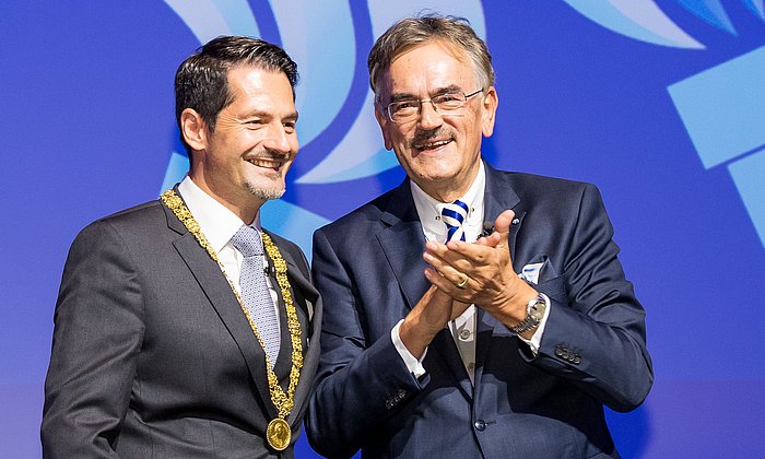 Wolfgang A. Herrmann und Thomas F. Hofmann auf der Bühne des Audimax der TUM. Hofmann trägt die Amtskette.