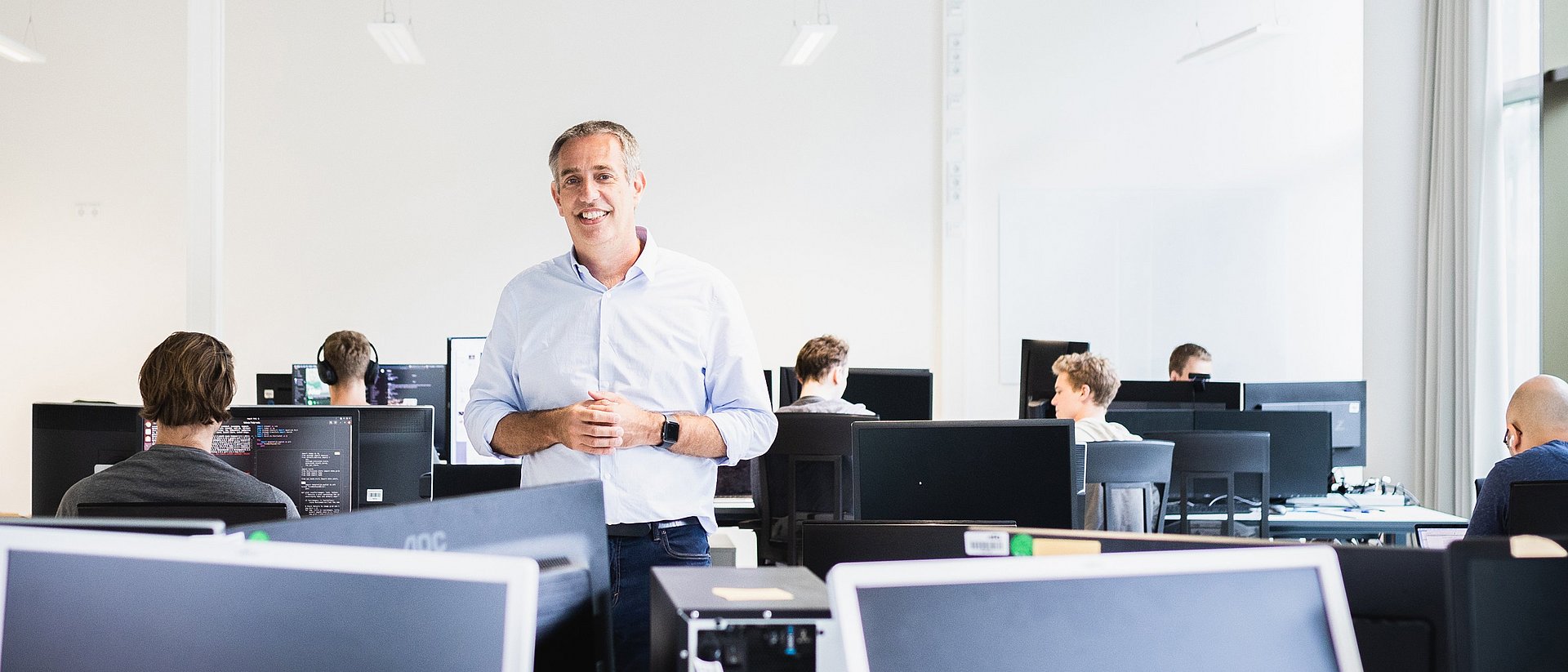 Prof. Daniel Rückert mit anderen Personen in einem Arbeitsraum mit Computern.