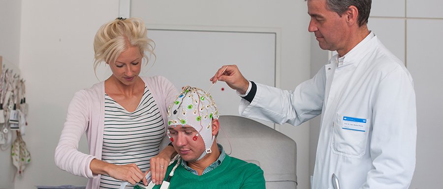 Laura Tiemann, Erstautorin der neuen Studie zur Schmerzwahrnehmung, bereitet zusammen mit Markus Ploner, Heisenberg-Professor für Human Pain Research an der TUM, eine Person für die EEG-Messung vor. (Bild: K. Bauer / TUM)