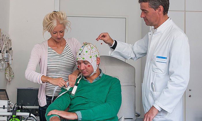 Laura Tiemann, first author of the new study about pain perception, prepares together with Markus Ploner, Heisenberg Professor for Human Pain Research, a volunteer for the EEG-measurements. (Image: K. Bauer / TUM)
