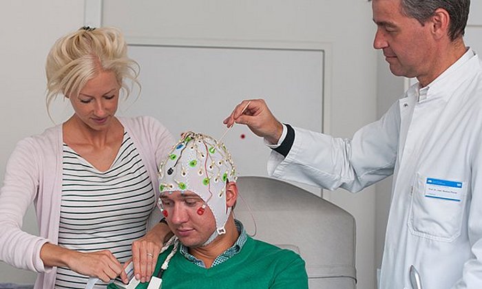 Laura Tiemann, Erstautorin der neuen Studie zur Schmerzwahrnehmung, bereitet zusammen mit Markus Ploner, Heisenberg-Professor für Human Pain Research an der TUM, eine Person für die EEG-Messung vor. (Bild: K. Bauer / TUM)