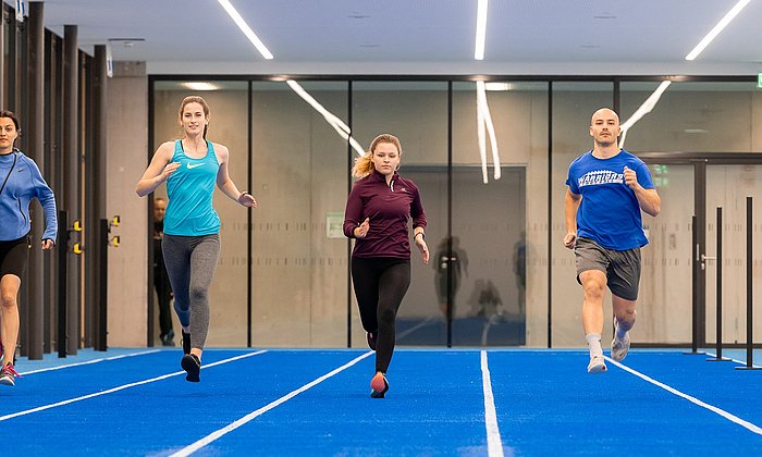 Vier Stueirende sprinten in einer der größten neuen Sporthallen.