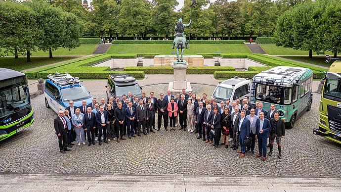 Teilnehmende des IAA Roundtable „Modellregionen für Autonomes Fahren im ÖPNV“  im Hof der Staatskanzlei vor autonom fahrenden Fahrzeugen