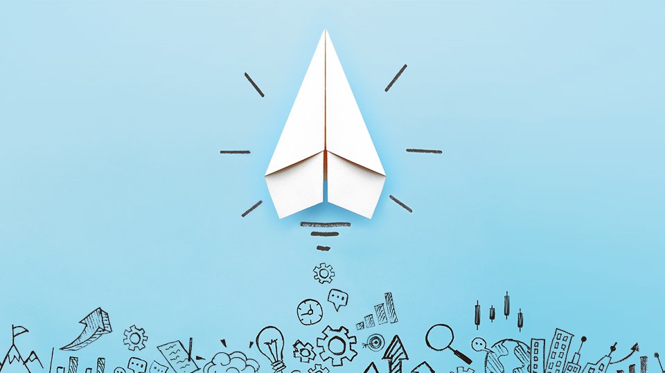 Academicus Ideas Competition A white paper airplane against a blue background, pencil sketches at the bottom of the picture.