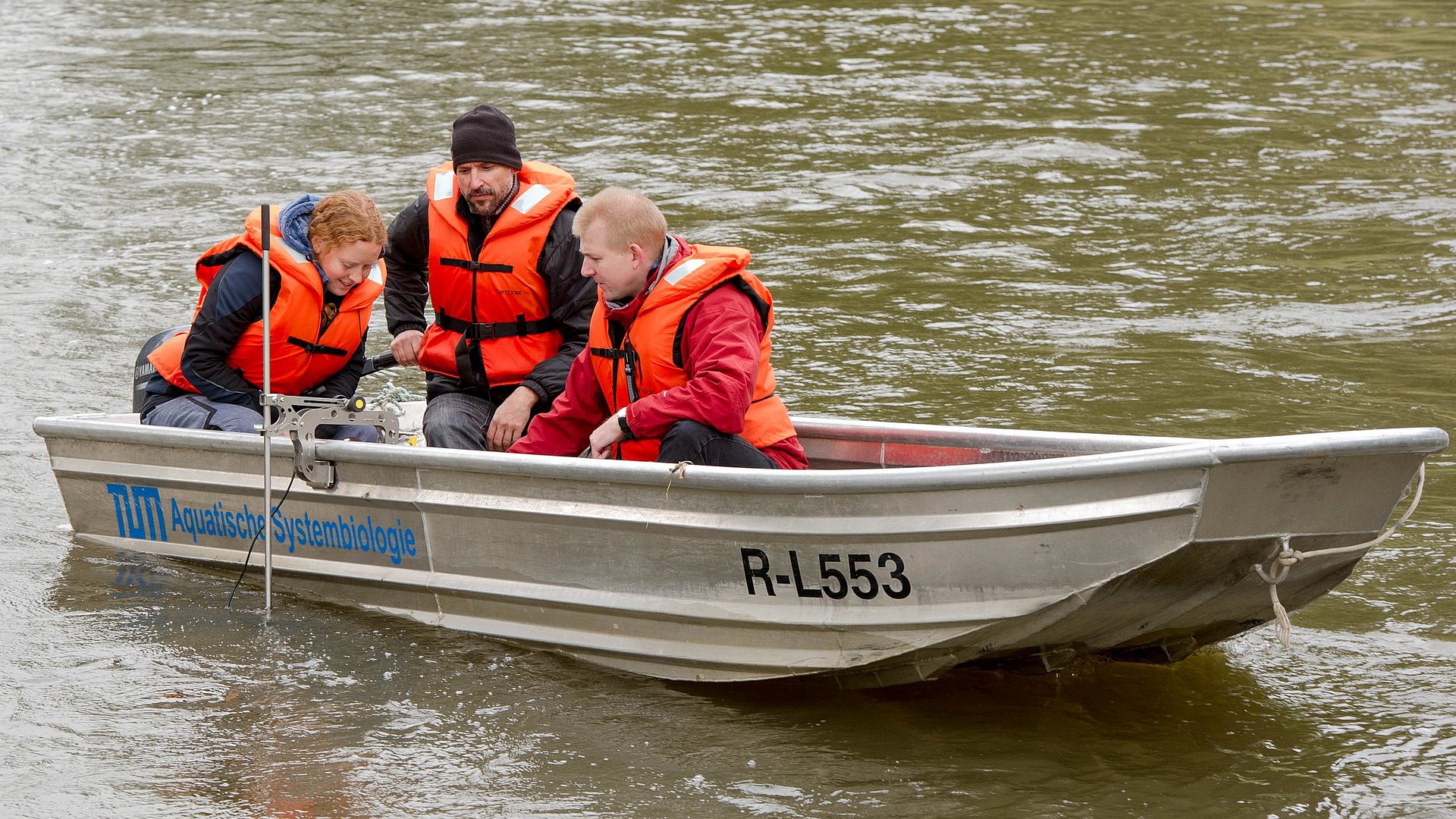 Dr. Melanie Müller, Dr. Joachim Pander and Prof. Jürgen Geist in a research boat on a river.