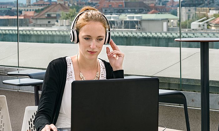 Studierende auf der Dachterrasse vor einem Laptop 