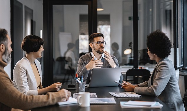 Vier Personen diskutieren an einem Tisch.