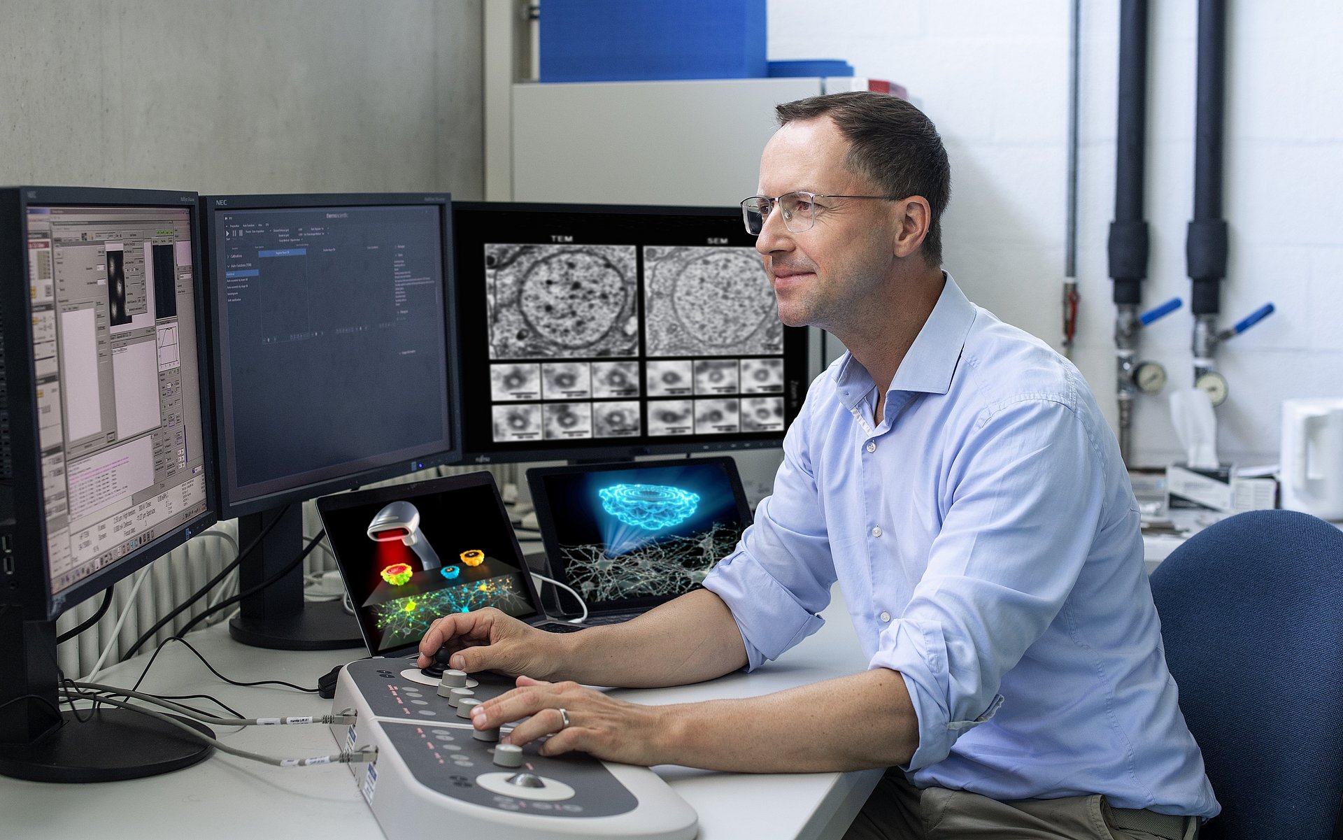 Prof. Gil Gregor Westmeyer working at the computer station next to an electron microscope.