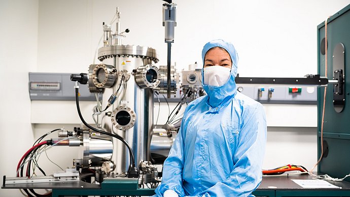 Die Professorin Eva Weig vor der Apparatur zum Aufdampfen der verschiedenen metallischen Schichten auf die Chips.