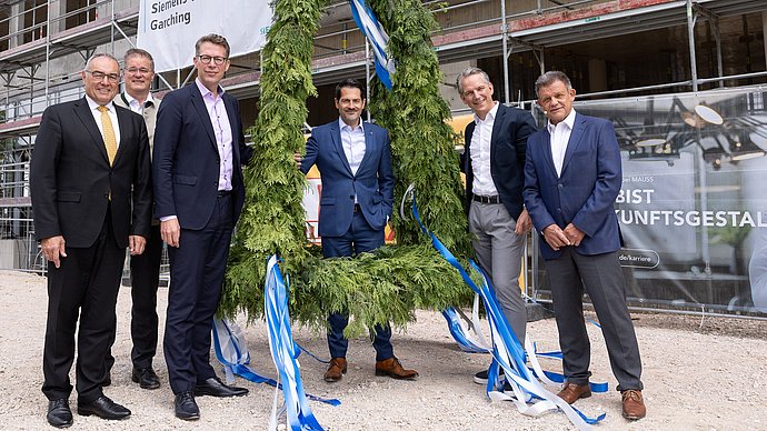 President Thomas F. Hofmann (middle), Chancellor Albert Berger (l.), State Minister Markus Blume (3.f.l.), Dr. Peter Körte and Dr. Zsolt Sluitner from Siemens (r.), and Garching mayor Dr. Dieter Gruchmann (2.f.l.) at the topping-out wreath for the Siemens Technology Center. 