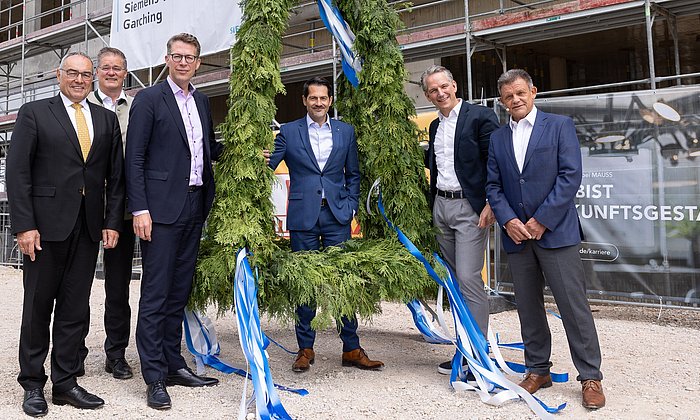 President Thomas F. Hofmann (middle), Chancellor Albert Berger (l.), State Minister Markus Blume (3.f.l.), Dr. Peter Körte and Dr. Zsolt Sluitner from Siemens (r.), and Garching mayor Dr. Dieter Gruchmann (2.f.l.) at the topping-out wreath for the Siemens Technology Center. 