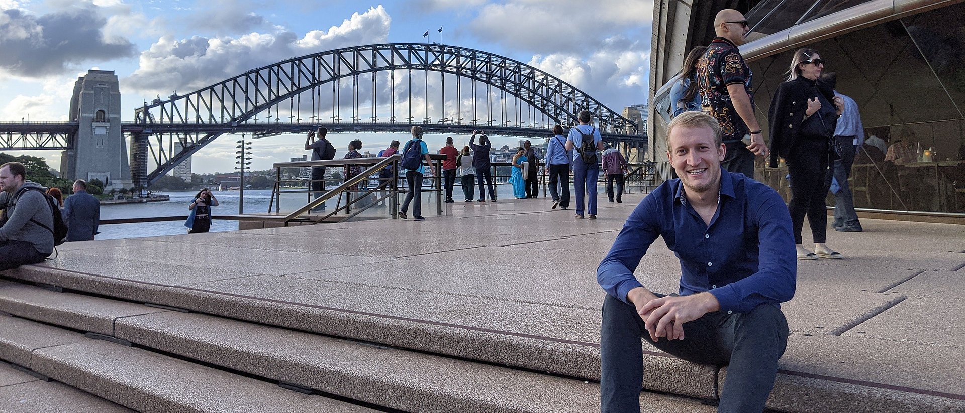 Dokorand Tobias Teschemacher sitzt vor einer Brücke in Brisbane, Australien. 