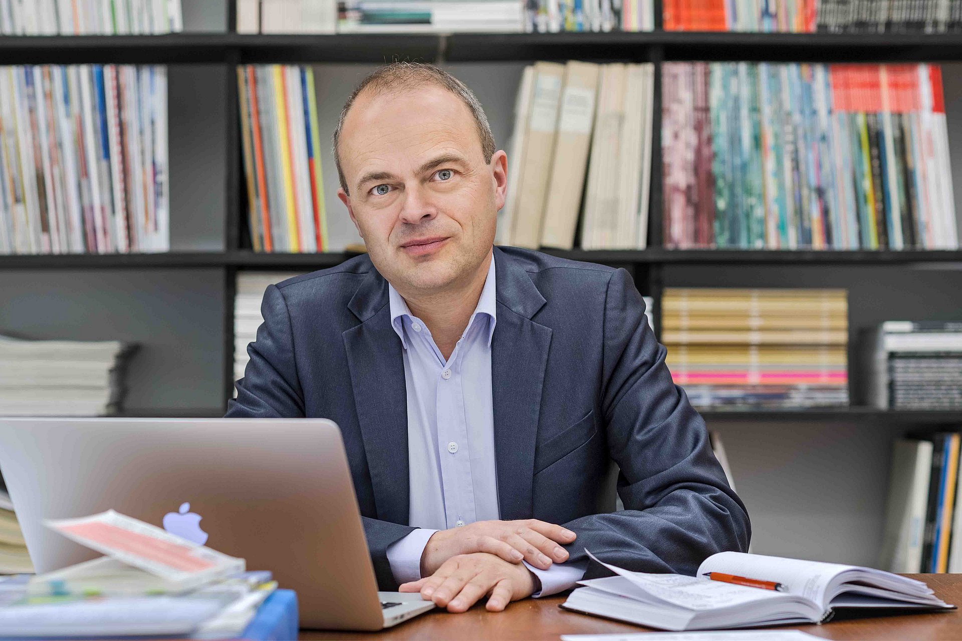 Prof. Stephan Trüby vor einem Bücherregal in seinem Büro.