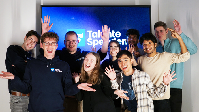 Eine Gruppe Studierender vor dem Logo von Talente Spenden e.V.