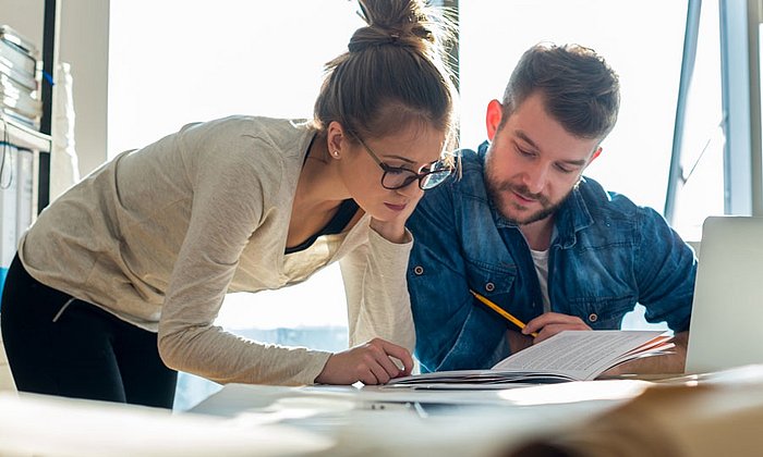 Eine Frau und ein Mann konzentrieren sich im Büro auf einen Text