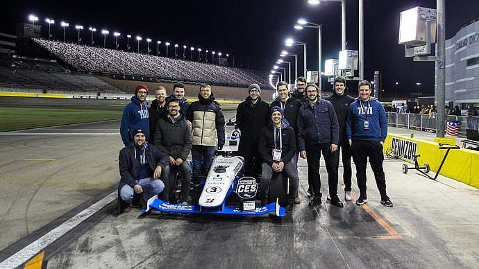 Eine Gruppe Wissenschaftler:innen stehen um einen Formel-Rennwagen.