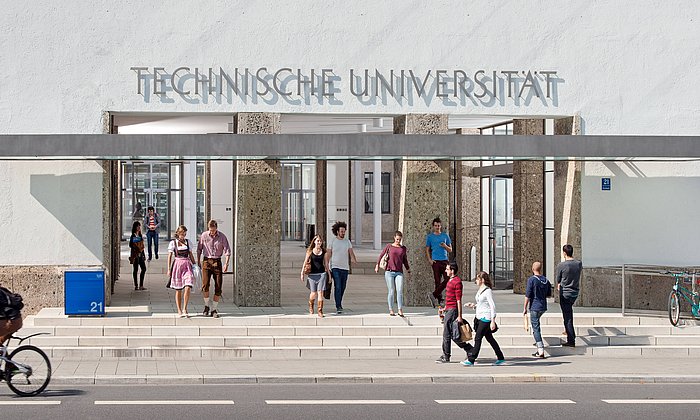 Students and people passing by in front of the main entrance of the Technical University of Munich.