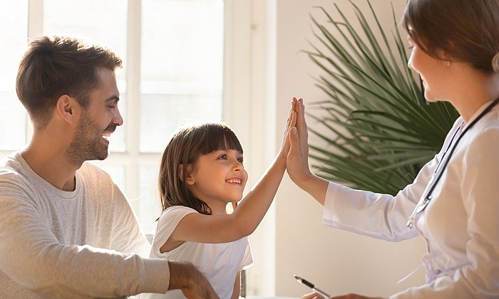 A child and a doctor give each other a "High 5"