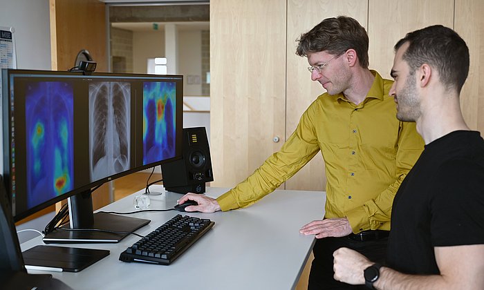 PD Dr. Tobias Lasser and Alessandro Wollek (front) are comparing a TMME saliency map (left screen) with a GradCAM saliency map.