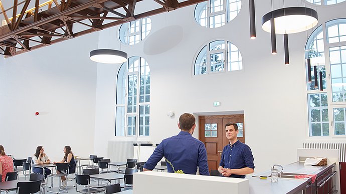 Students chat and work together in the foyer of one of the StudiTUM houses.