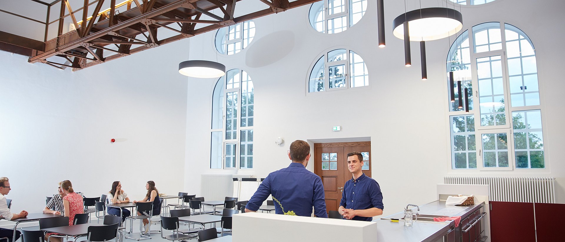 Studierende unterhalten sich und arbeiten gemeinsam im Foyer eines der StudiTUM-Häuser.