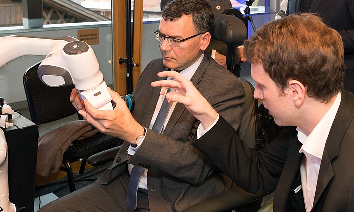 Bei der Eröffnung erprobt Staatsminister Dr. Florian Hermann einen Rasier-Roboter. Im Hintergrund unterhalten sich Garmisch-Partenkirchens 1. Bürgermeisterin Dr. Sigrid Meierhofer und Prof. Sami Haddadin.