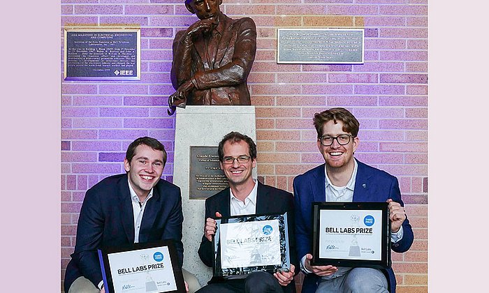 TUM-Forscher Fabian Steiner, Georg Böcherer, und Patrick Schulte (vlnr) vor der Statue von Claude Shannon, Vater der Informationstheorie.