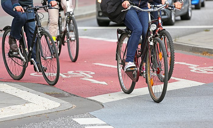 Radfahrer fahren auf einem rot markiertem Radweg.