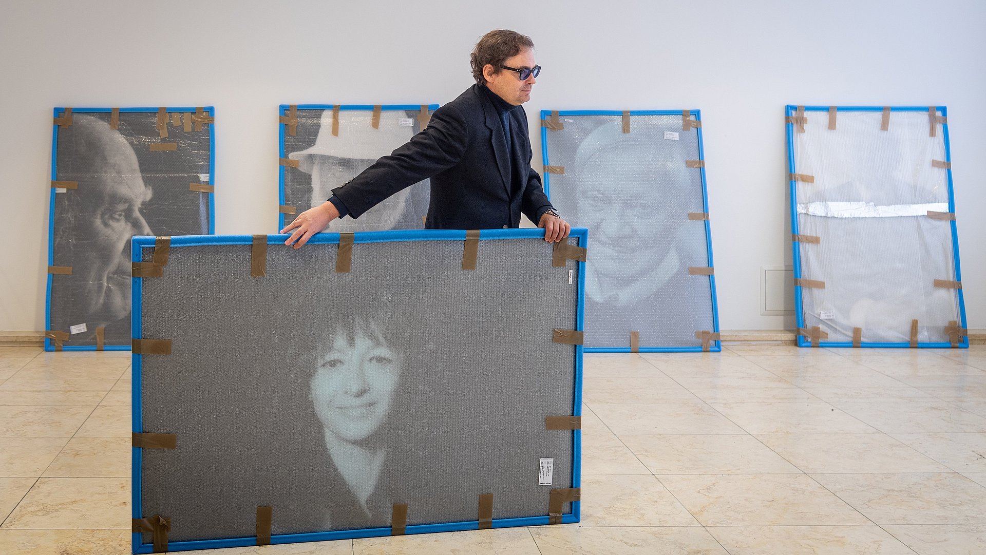 Fotograf Peter Badge beim Aufbau der Ausstellung Nobel Heros in der Imathalle mit Prof. Felix Mayer; Schwarz-Weiß Porträt der Nobelpreisträgerin für Chemie 2020, Emmanuelle Marie Charpentier 