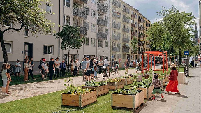 People meet in a Munich street that has been greened with plant boxes