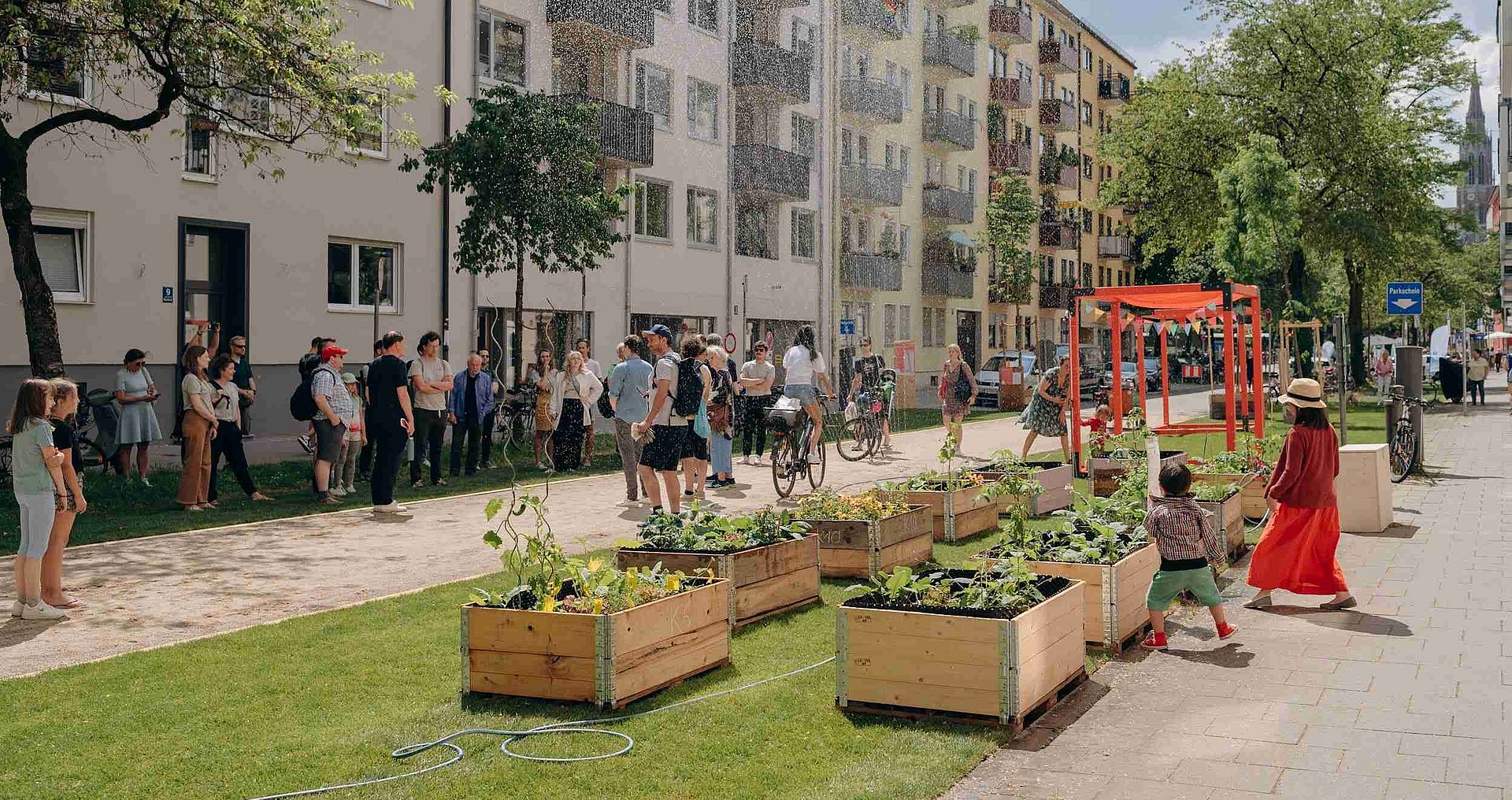 People meet in a Munich street that has been greened with plant boxes