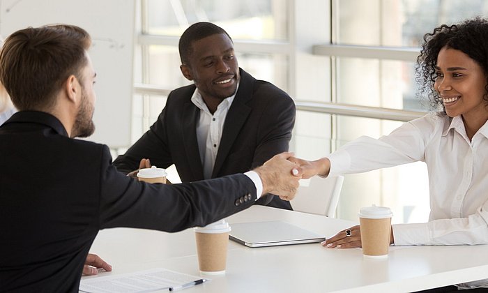 Geschäftspartnerin- und Partner geben sich die Hand. 