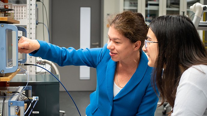 Eva Weig (left) and doctoral candidate Maria Kallergi discuss the measurements of a nanostring in front of a Vector-Network-Analyzer.