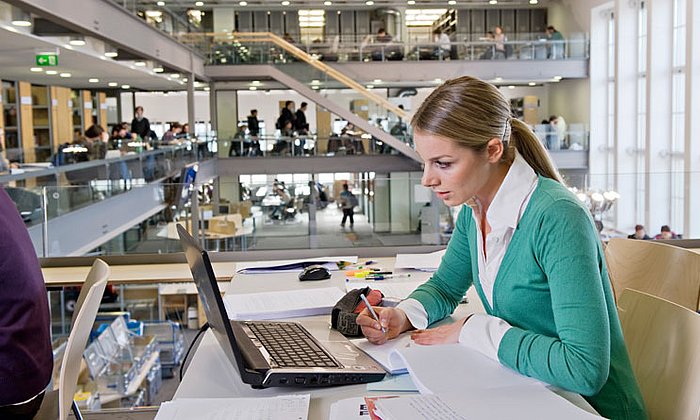 Frau recherchiert an einem Computer in der Universitätsbibliothek.