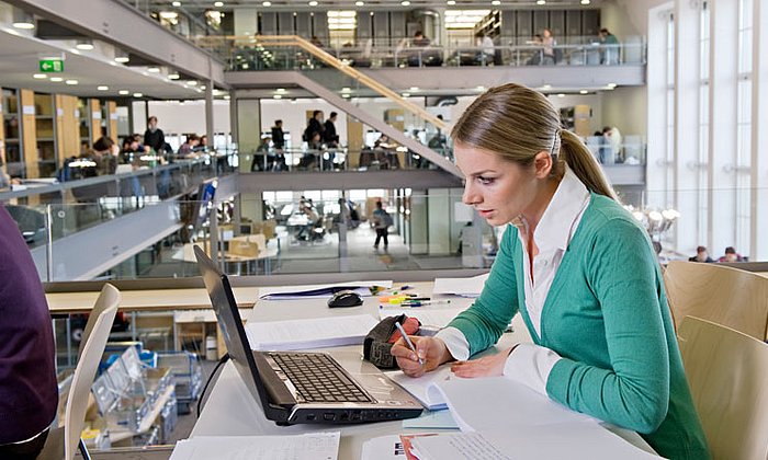 Woman researching on a laptop in the university library. 