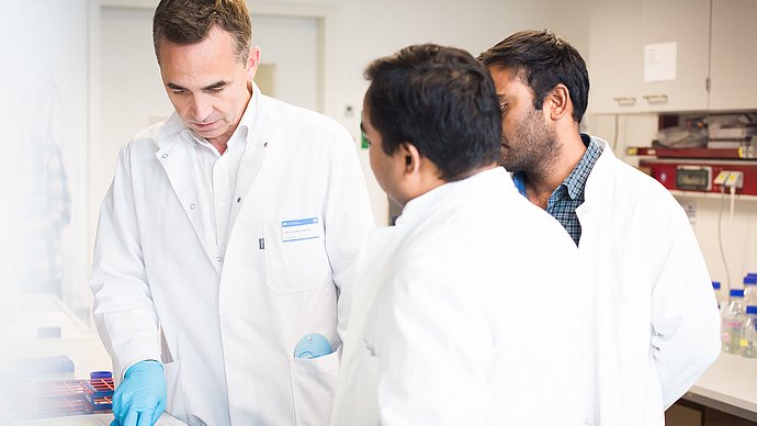 Physician Prof. Bernhard Hemmer at work with two employees.